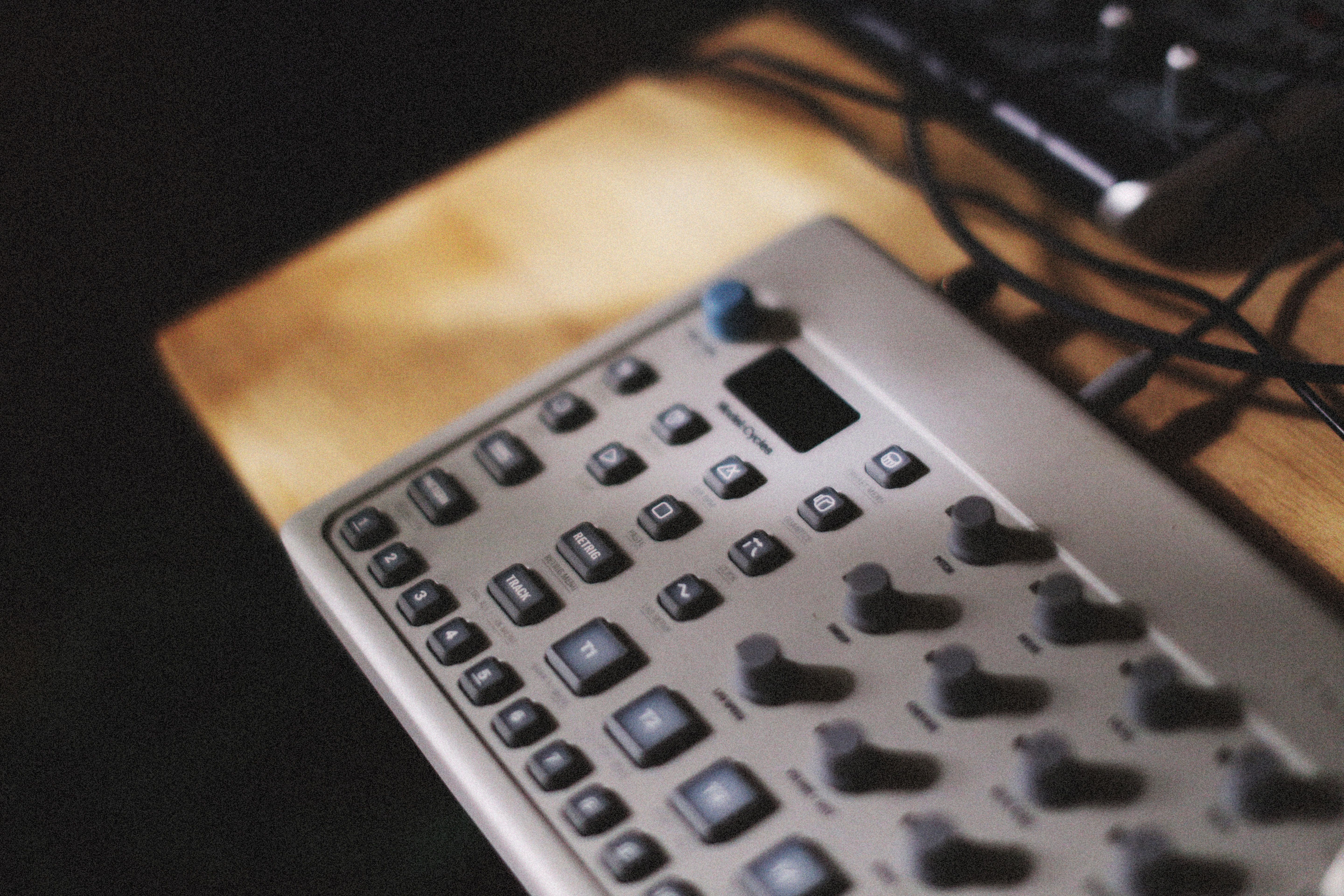 Detailed view of a silver audio mixing console on a wooden desk, highlighting buttons and controls.