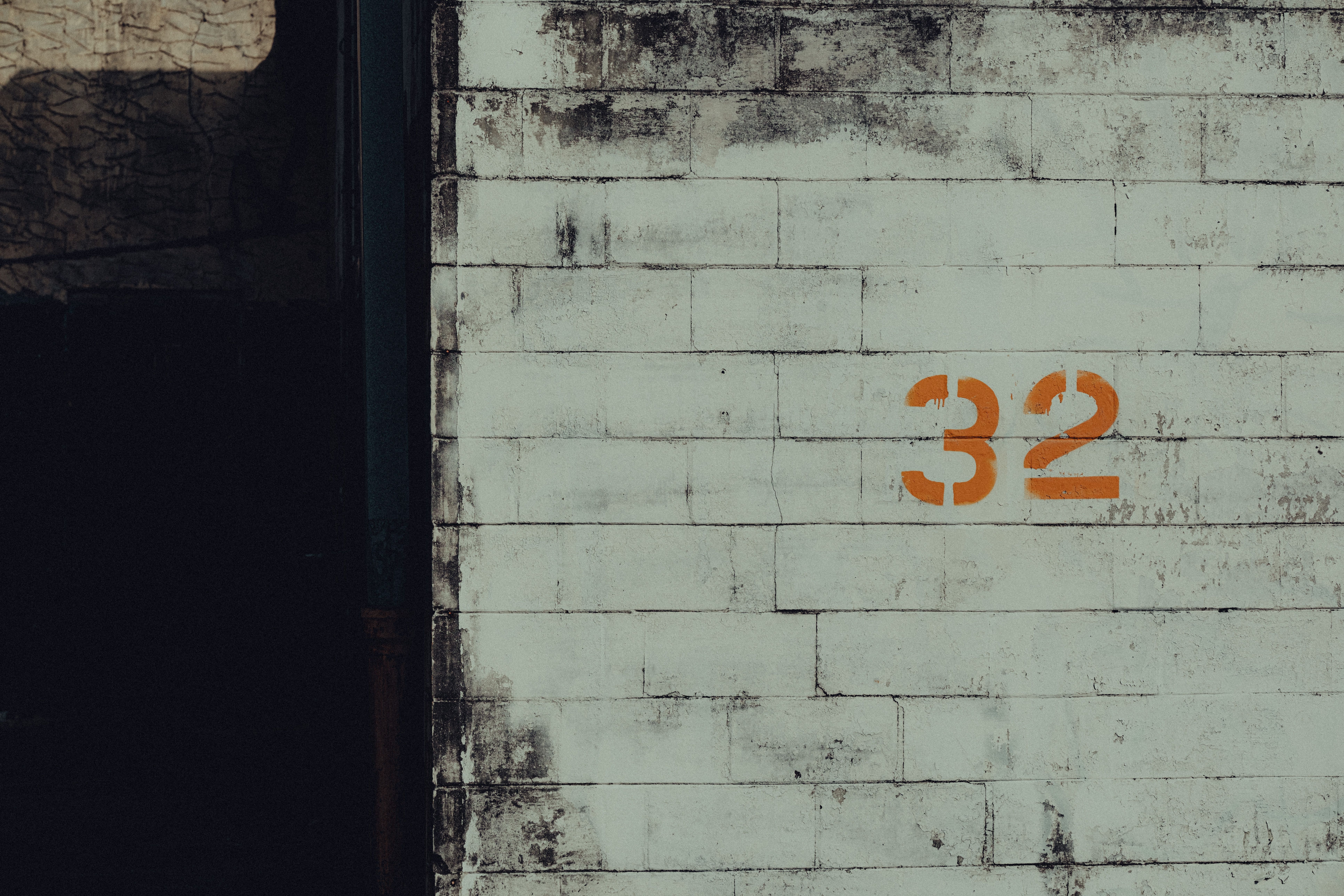 An aged urban wall featuring the number 32 in orange graffiti, offering a gritty cityscape aesthetic.