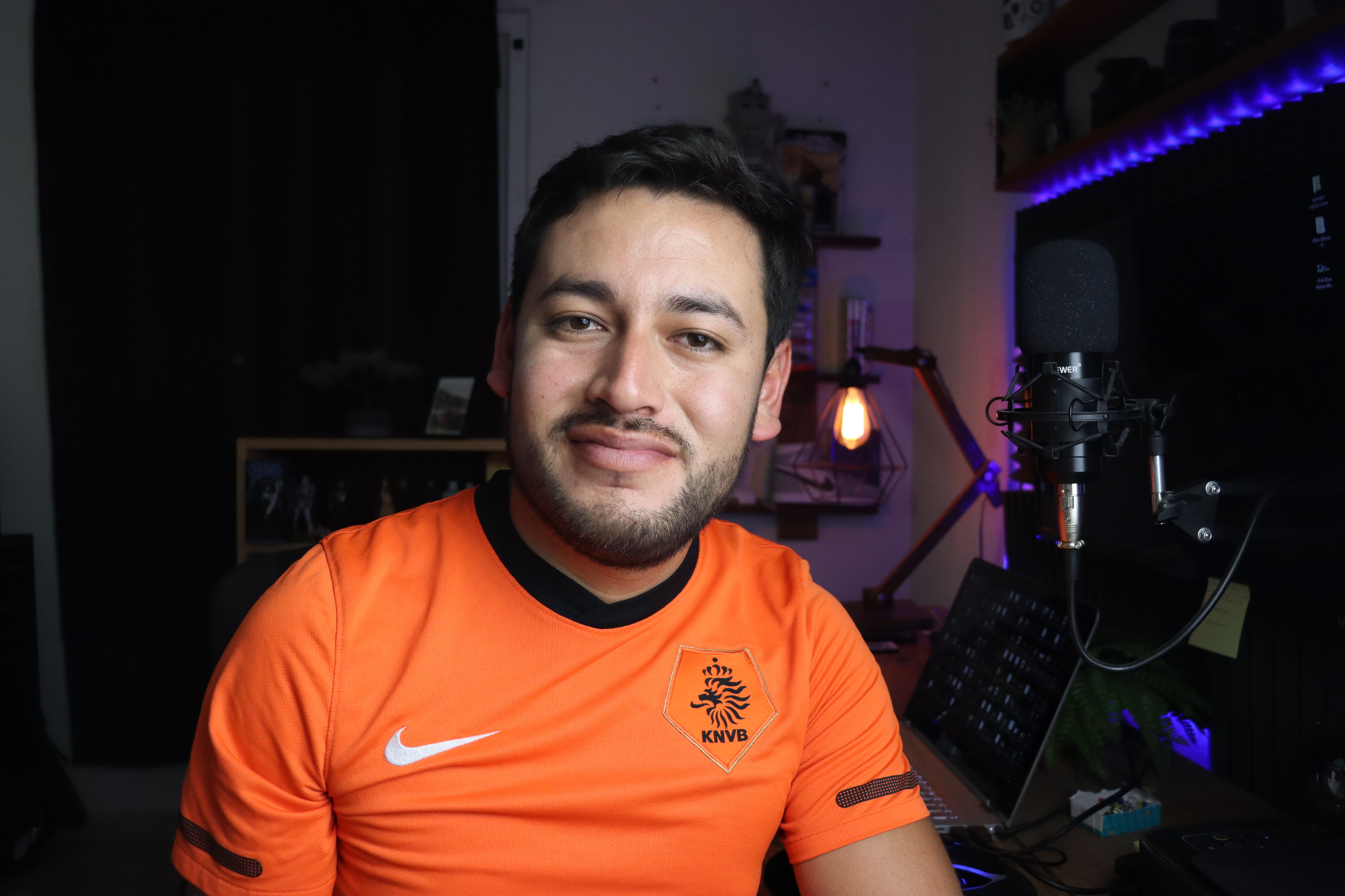Portrait of a smiling man in a home studio setup with a microphone, showcasing creativity and comfort.