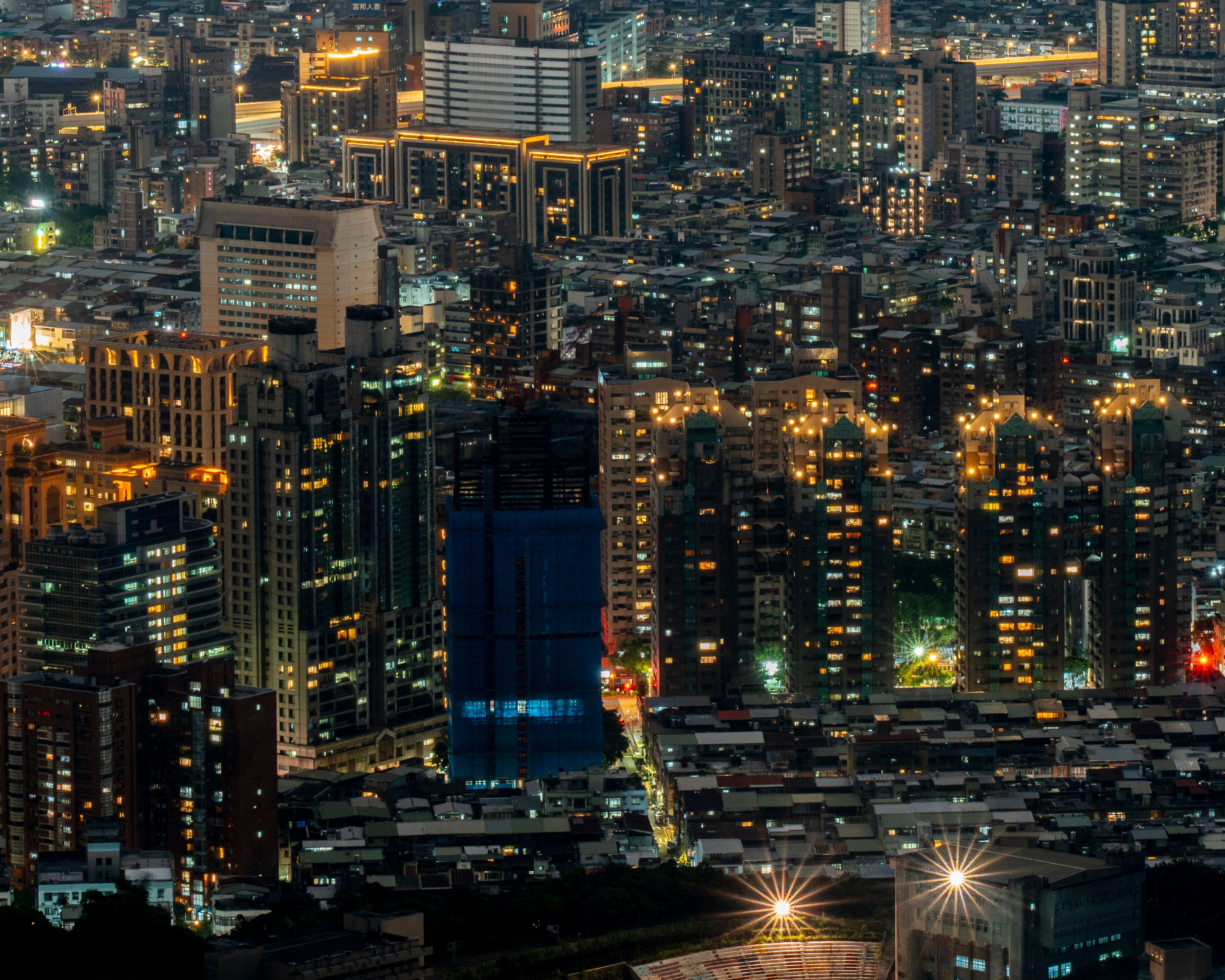 High angle night view of a brightly lit urban cityscape with skyscrapers.