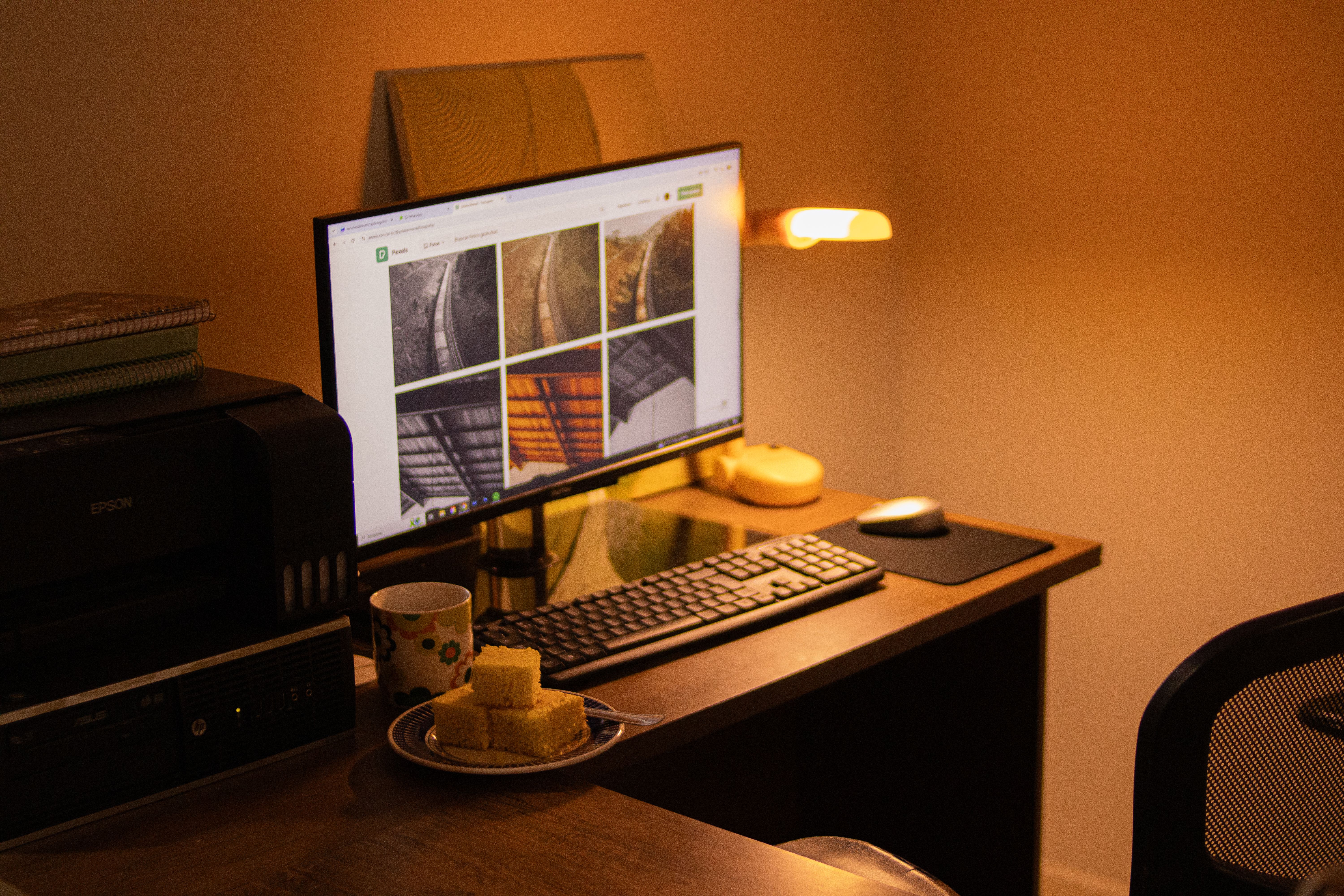 Warm-toned home office with computer setup, snacks, and ambient lighting.