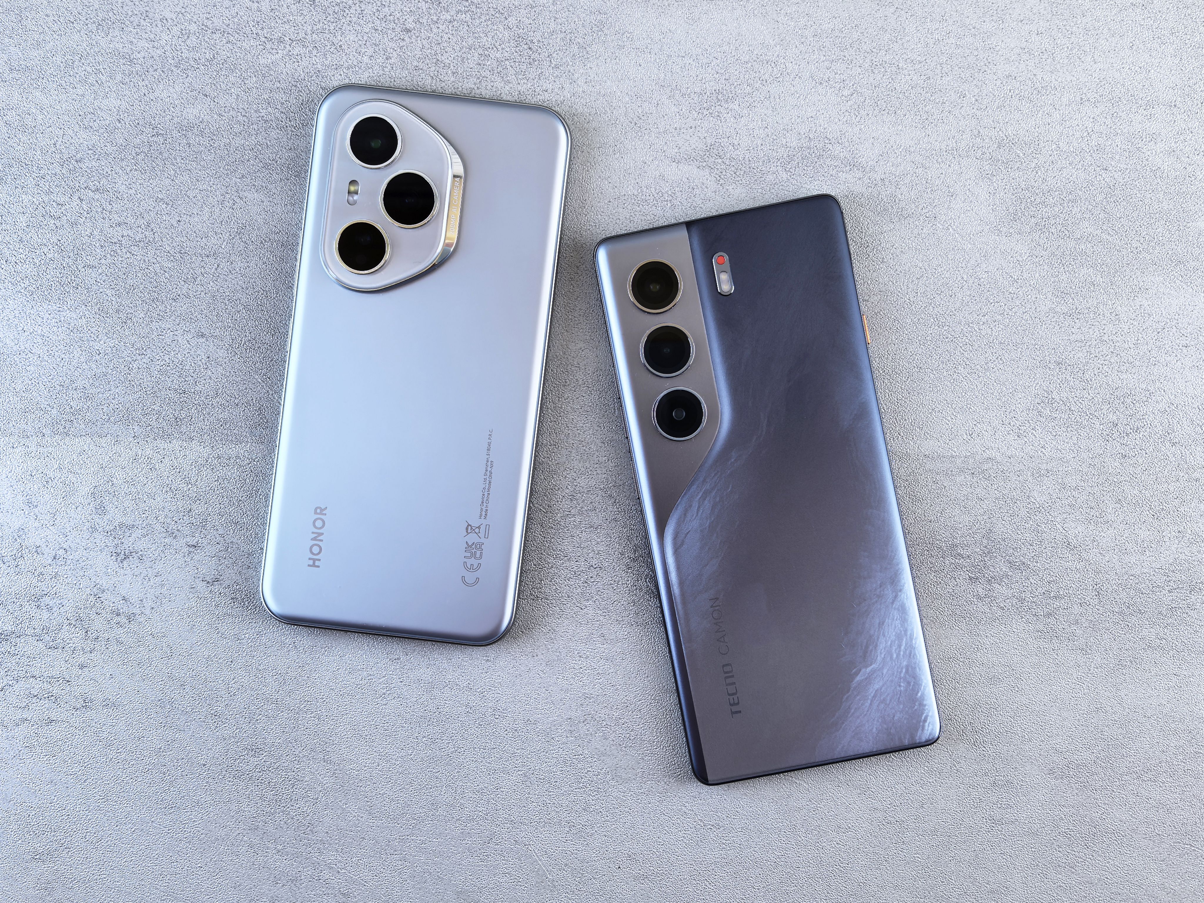 Two modern smartphones displayed on a concrete surface, showcasing different camera designs and styles.
