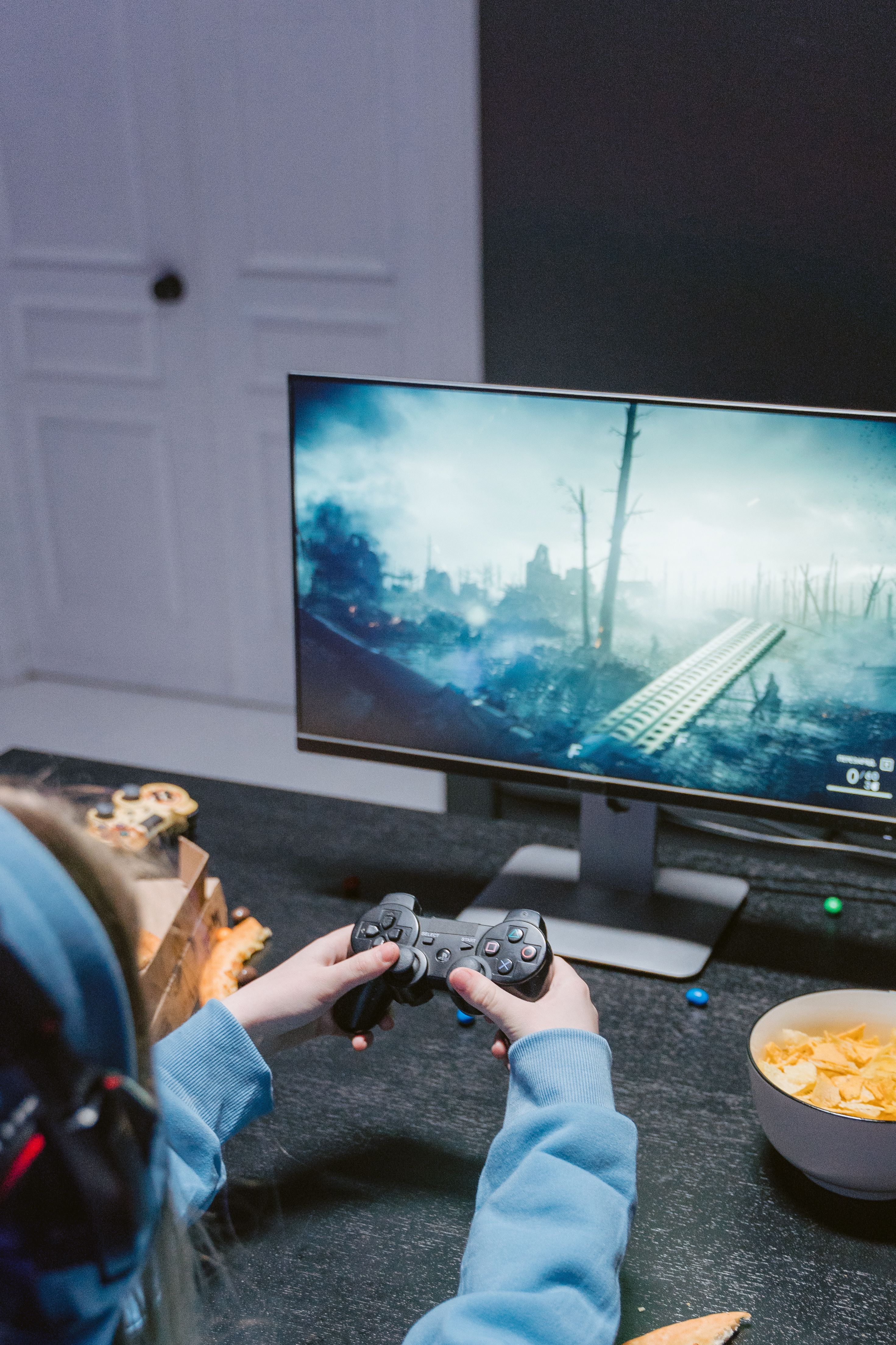 Focused teen playing a video game with controller at home, wearing headphones.