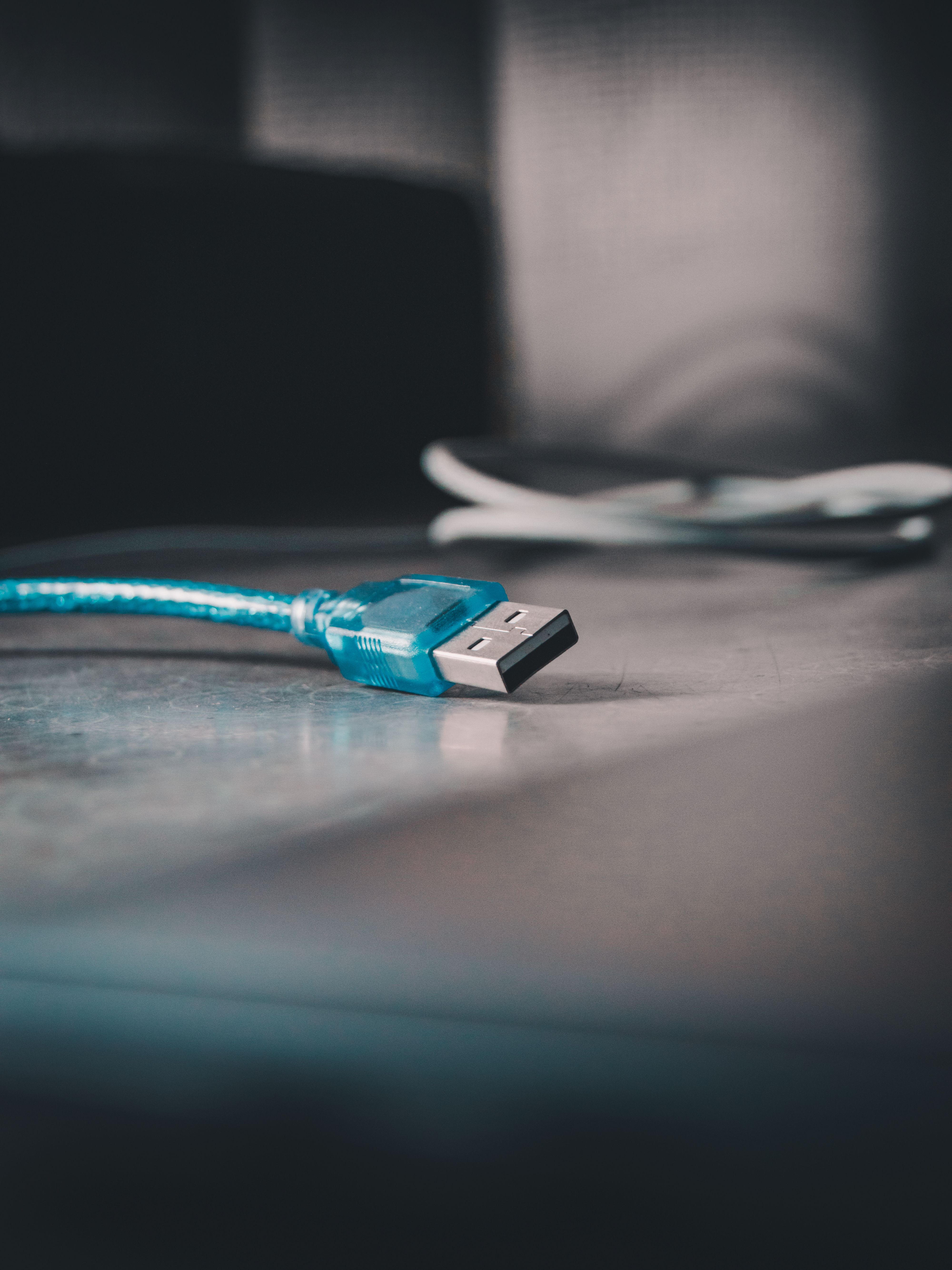 A detailed view of a blue USB cable lying on a reflective surface indoors.