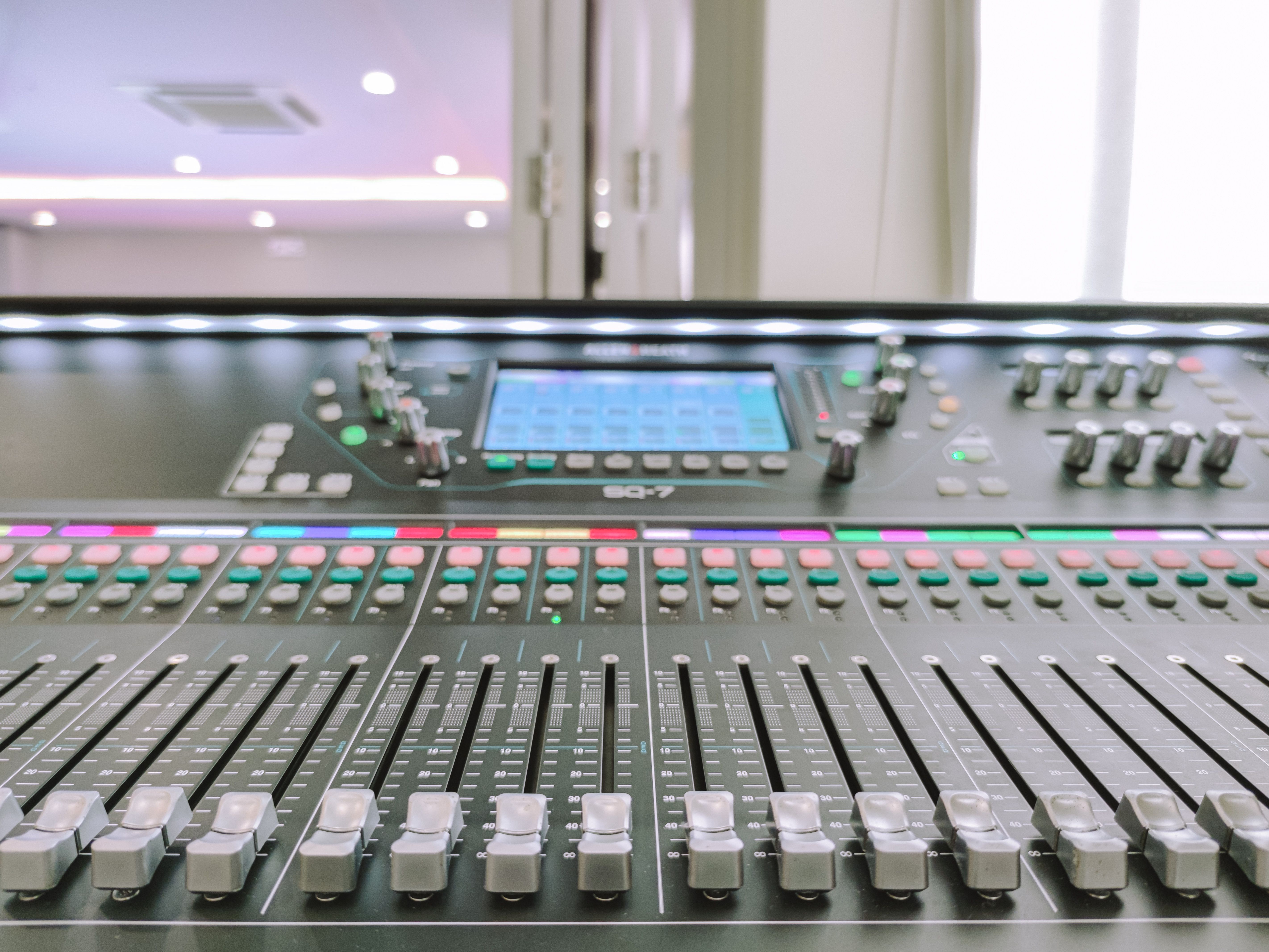 Close-up of an advanced audio mixer console with slide controls and digital display.