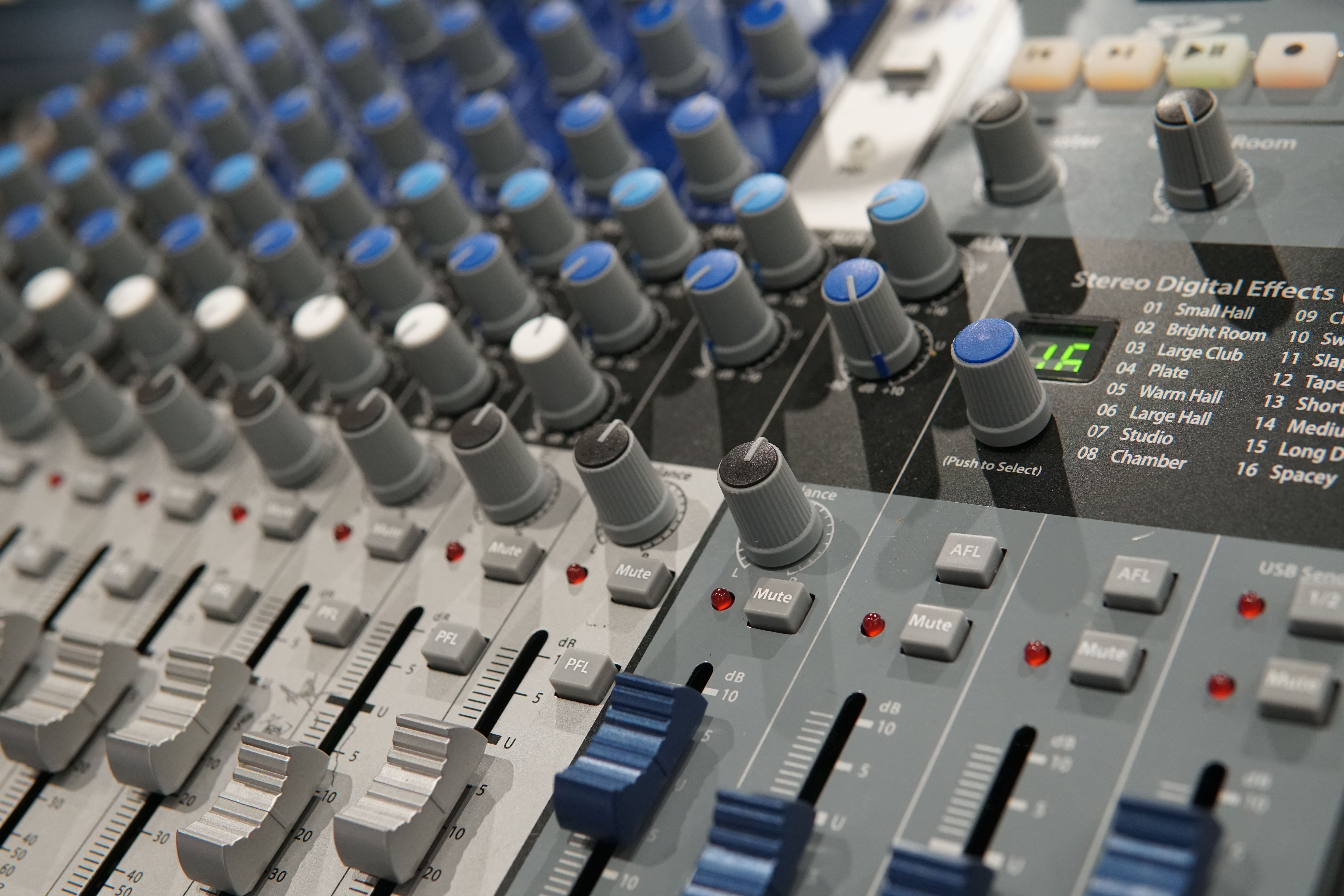 Detailed view of a modern audio mixing console with knobs and faders for sound engineering.