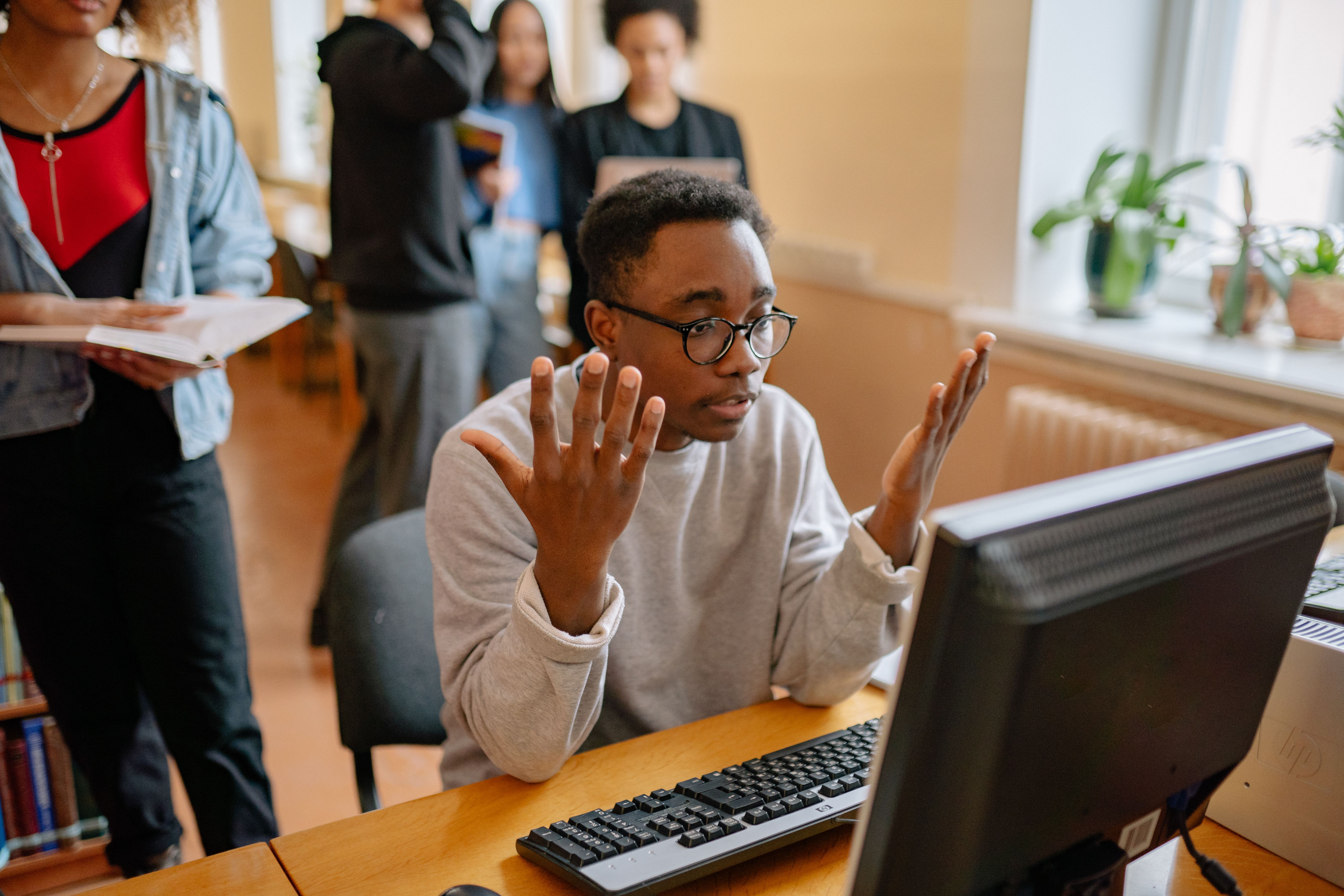 Young male office worker gesturing in frustration during a meeting at a desk.